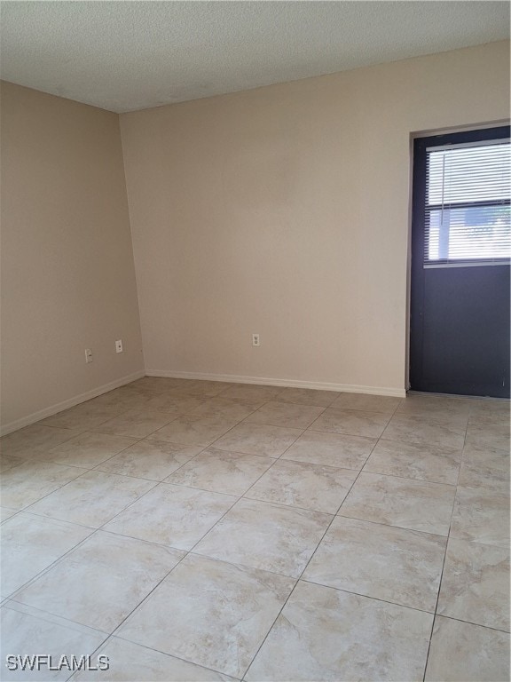 empty room featuring light tile patterned floors and a textured ceiling