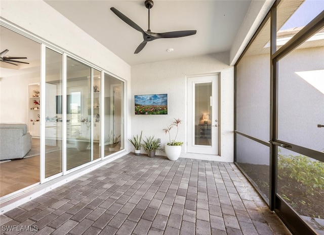 unfurnished sunroom featuring ceiling fan