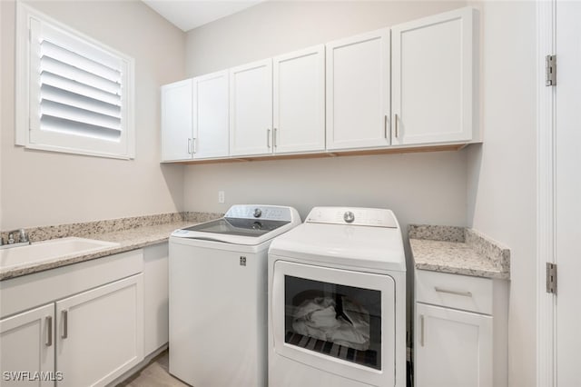 laundry area featuring washer and dryer, cabinets, and sink