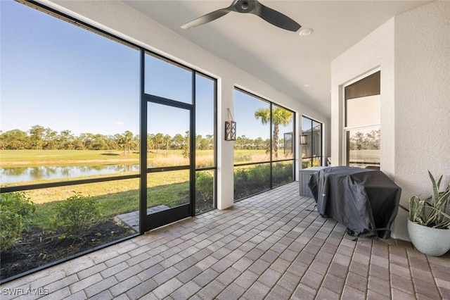 sunroom / solarium featuring ceiling fan and a water view