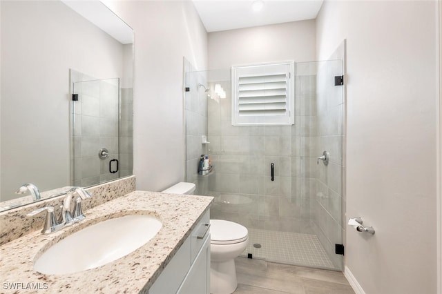 bathroom featuring hardwood / wood-style floors, vanity, toilet, and a shower with shower door