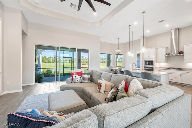 living room featuring a wealth of natural light, ceiling fan, and light wood-type flooring