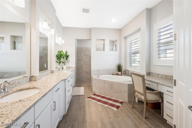 bathroom featuring tiled tub, hardwood / wood-style floors, and vanity