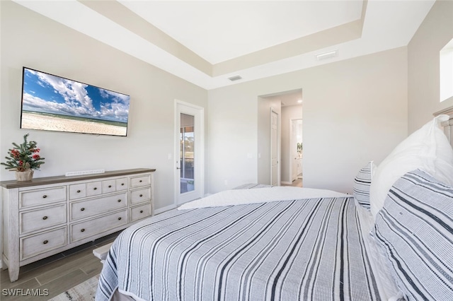 bedroom with dark hardwood / wood-style flooring and a tray ceiling