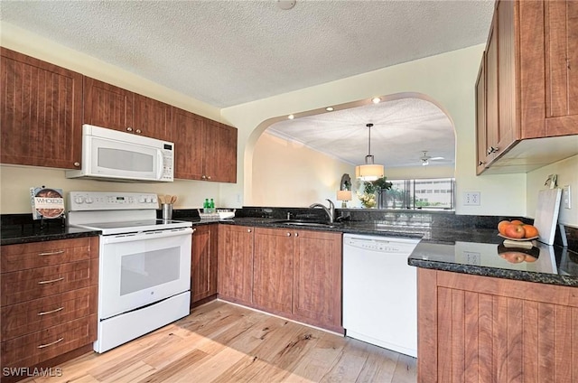 kitchen with pendant lighting, white appliances, sink, and light hardwood / wood-style flooring