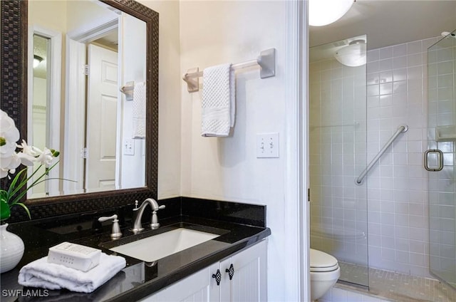 bathroom with vanity, toilet, and a shower with door