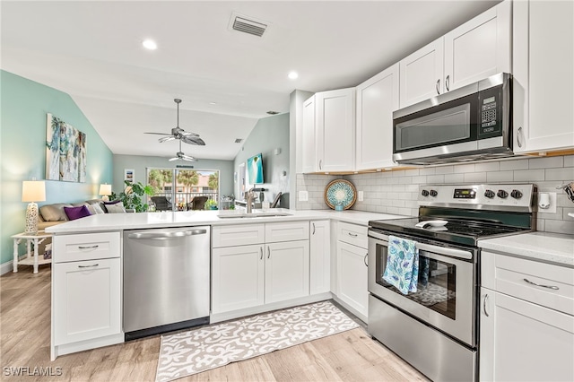 kitchen featuring white cabinets, kitchen peninsula, lofted ceiling, and stainless steel appliances