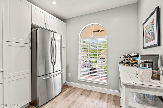 kitchen with white cabinets, light hardwood / wood-style floors, and stainless steel refrigerator