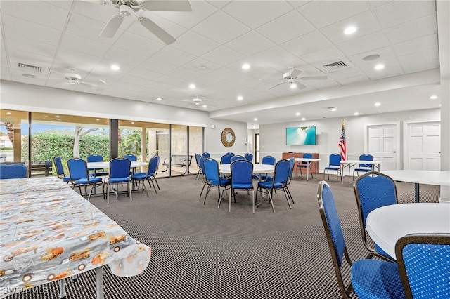 carpeted dining area with a paneled ceiling