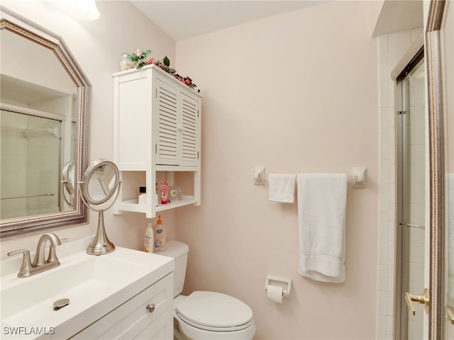 bathroom with vanity, toilet, and a shower with door