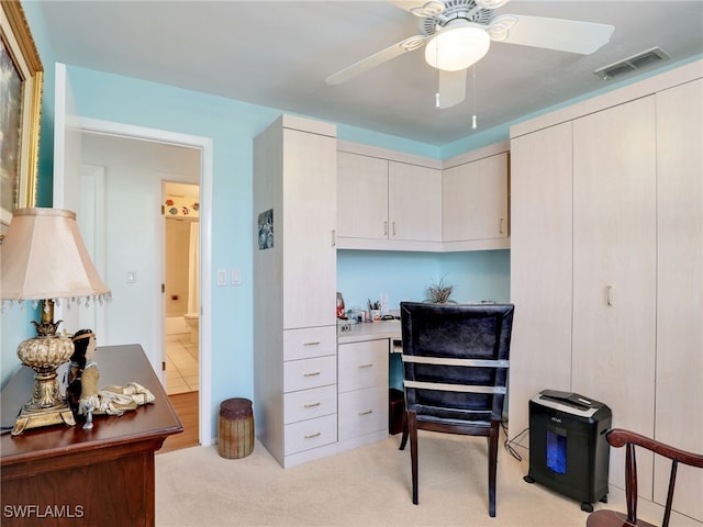 carpeted home office featuring ceiling fan and built in desk