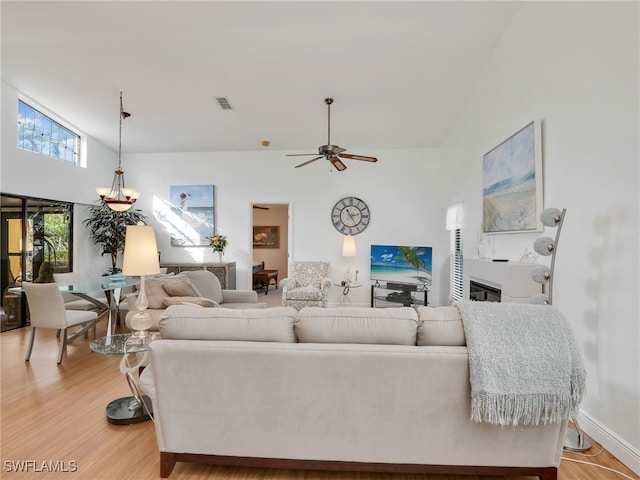 living room featuring ceiling fan, a high ceiling, and light hardwood / wood-style flooring