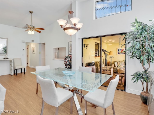 dining room with ceiling fan, a high ceiling, and light hardwood / wood-style flooring