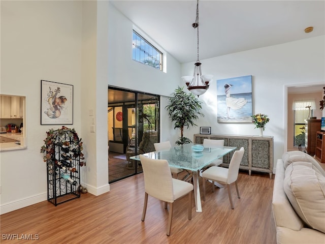 dining area with a high ceiling, hardwood / wood-style flooring, and a healthy amount of sunlight