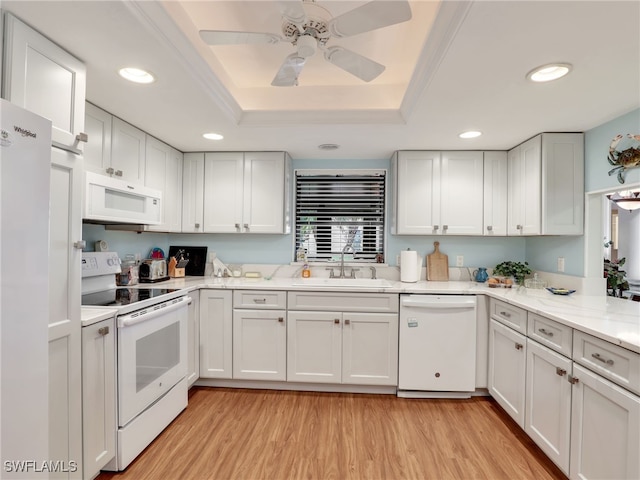 kitchen featuring white appliances, white cabinets, sink, light hardwood / wood-style flooring, and a tray ceiling