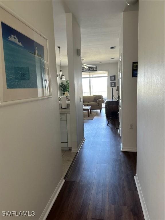 hall with baseboards and dark wood-type flooring