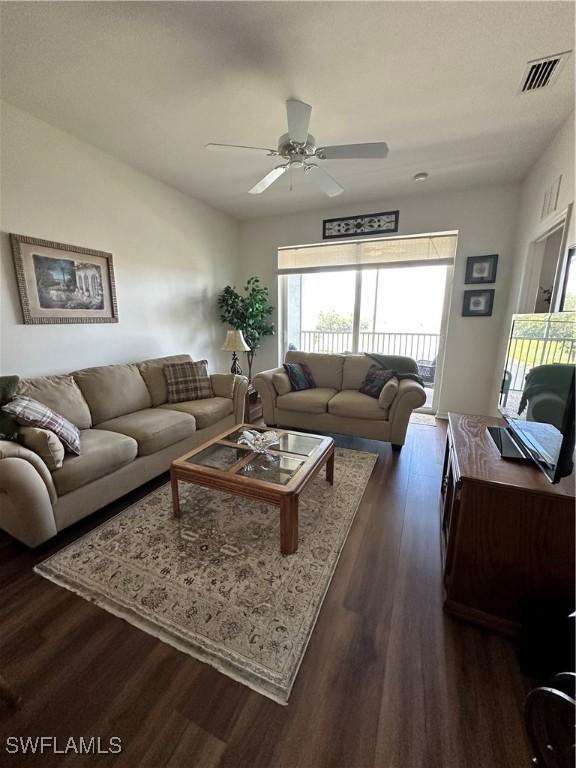 living room featuring a ceiling fan, dark wood-style floors, and visible vents