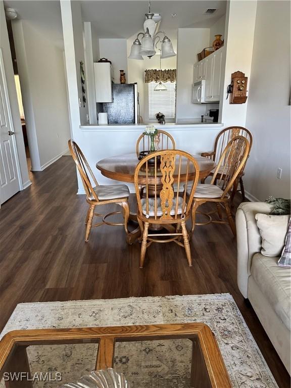 dining space with a chandelier and dark hardwood / wood-style flooring