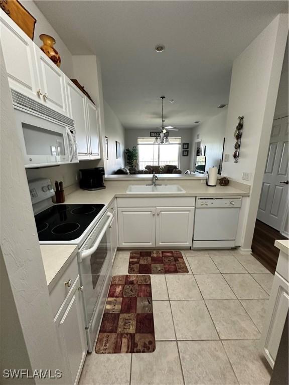 kitchen with sink, white appliances, kitchen peninsula, and white cabinets