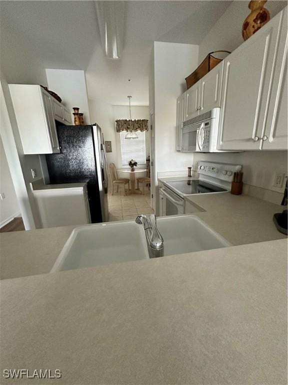 kitchen with decorative light fixtures, white cabinetry, sink, a chandelier, and white appliances