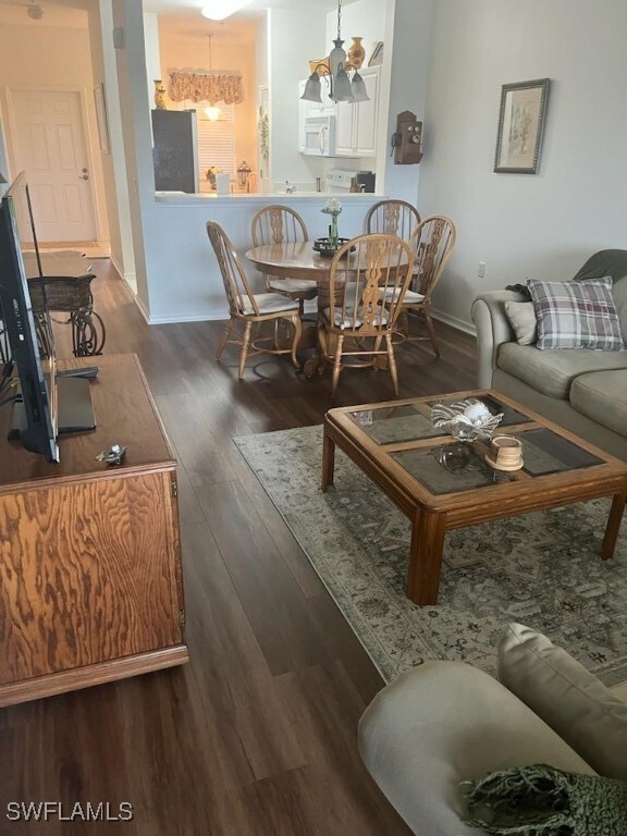 living room with an inviting chandelier and dark wood-type flooring