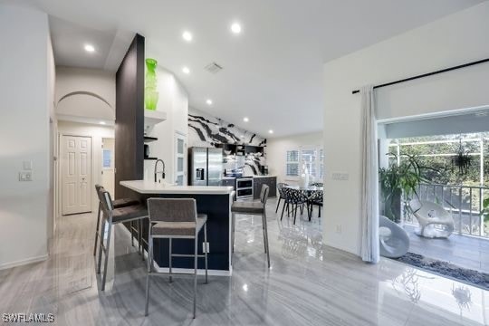 kitchen with kitchen peninsula, stainless steel fridge, a kitchen bar, and sink