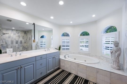 bathroom with vanity and shower with separate bathtub