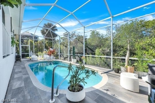 view of pool featuring glass enclosure and a patio area