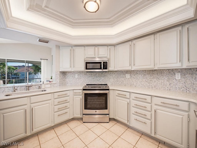 kitchen featuring a raised ceiling, white cabinets, light tile patterned flooring, and appliances with stainless steel finishes