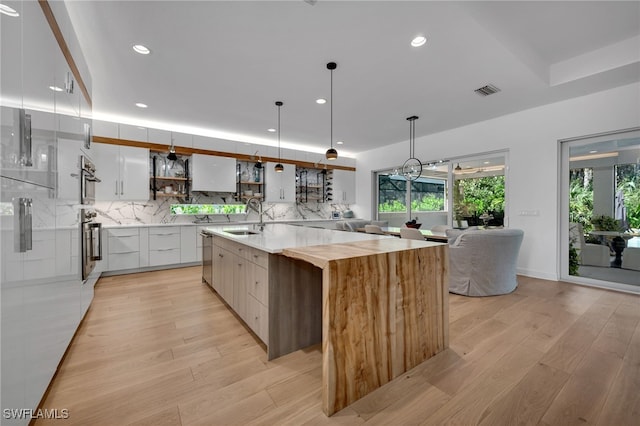 kitchen with pendant lighting, a large island, white cabinetry, a sink, and modern cabinets