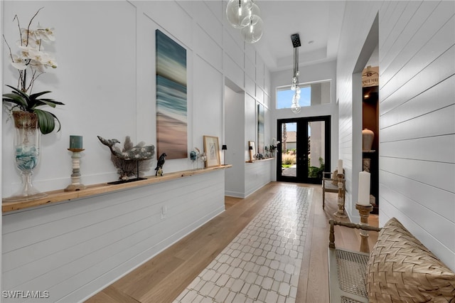 entrance foyer featuring light wood-style floors, french doors, and a towering ceiling