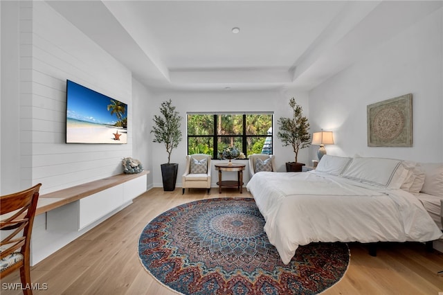 bedroom featuring light wood-style flooring and a raised ceiling