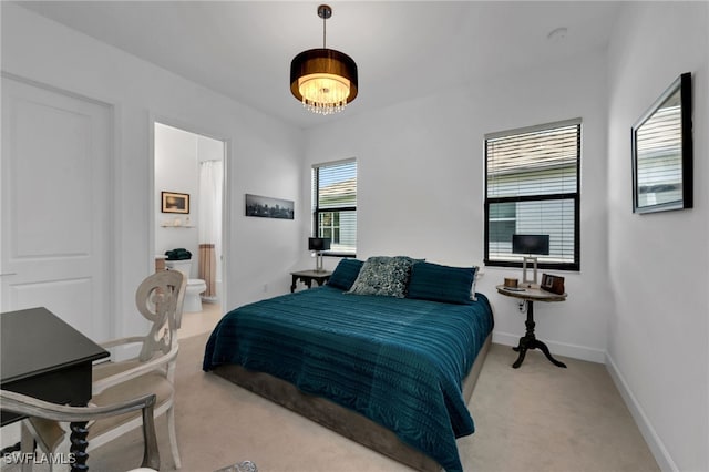 bedroom featuring light carpet, connected bathroom, and baseboards