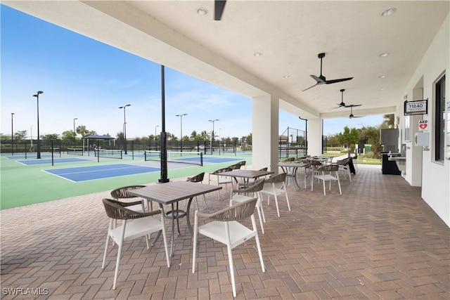 view of patio / terrace with a tennis court, ceiling fan, and fence