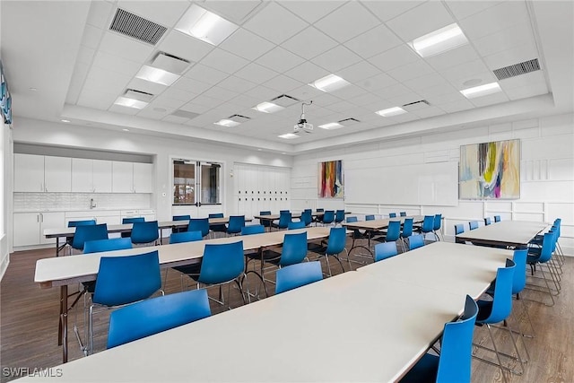 interior space with a paneled ceiling, visible vents, and dark wood-type flooring