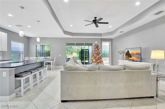 tiled living room featuring a tray ceiling and ceiling fan