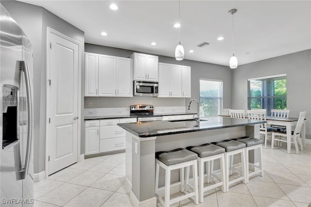 kitchen featuring appliances with stainless steel finishes, a center island with sink, white cabinetry, and sink