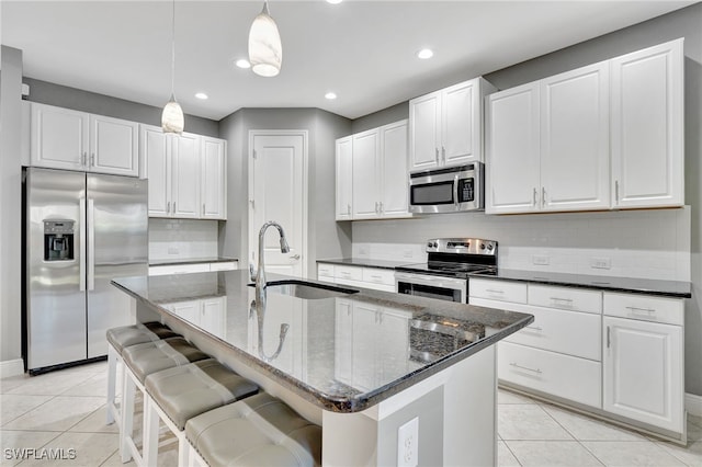 kitchen featuring hanging light fixtures, sink, stainless steel appliances, and a center island with sink