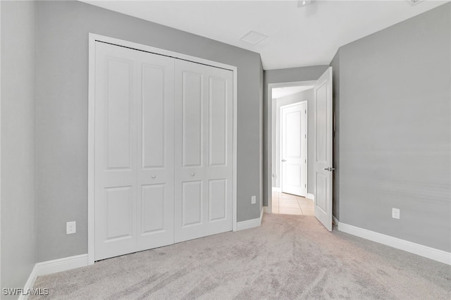 unfurnished bedroom with a closet and light colored carpet