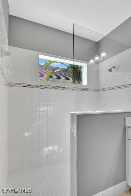 bathroom featuring tiled shower, vanity, and plenty of natural light