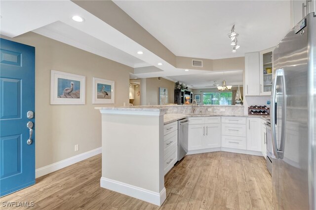 kitchen with kitchen peninsula, stainless steel appliances, white cabinets, and light stone countertops