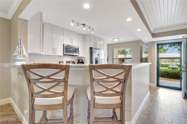 kitchen featuring stainless steel appliances, white cabinetry, and a breakfast bar area