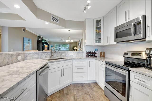 kitchen featuring white cabinets, sink, light stone counters, kitchen peninsula, and stainless steel appliances