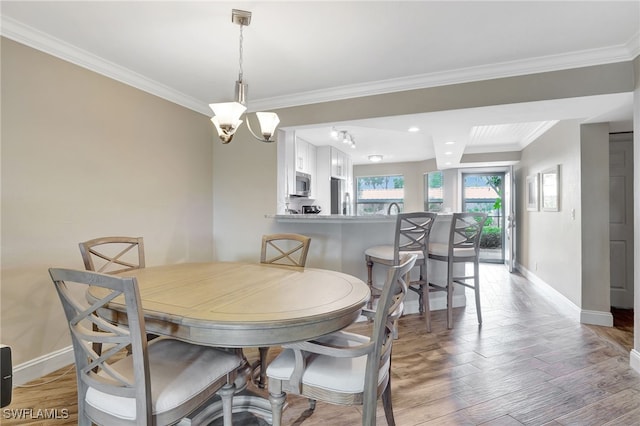 dining room with hardwood / wood-style flooring, crown molding, and an inviting chandelier