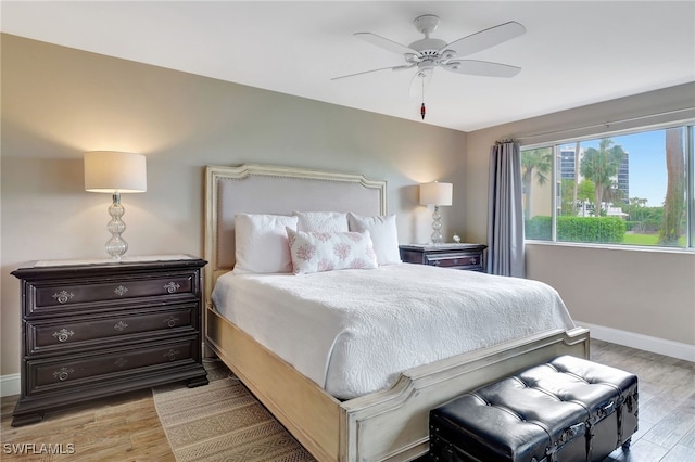 bedroom with a ceiling fan, light wood-style flooring, and baseboards