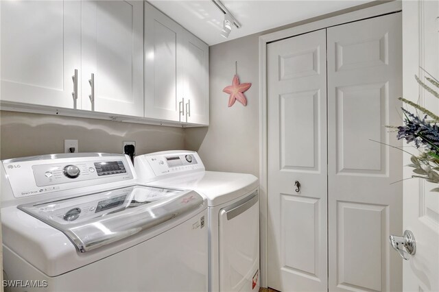 washroom with track lighting, cabinets, and washing machine and clothes dryer