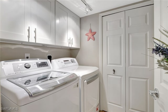 washroom featuring cabinet space, track lighting, and independent washer and dryer