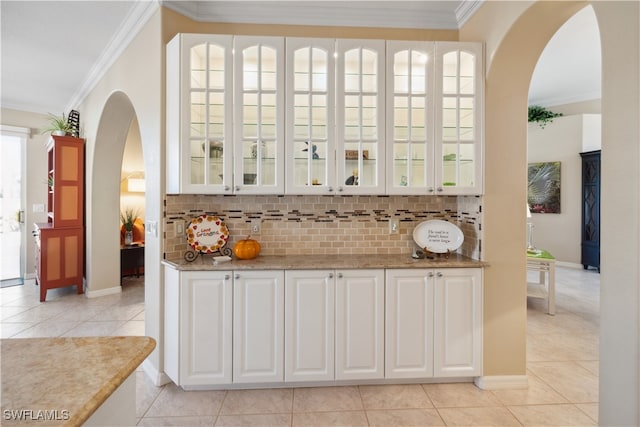 bar with white cabinets, light tile patterned flooring, and ornamental molding