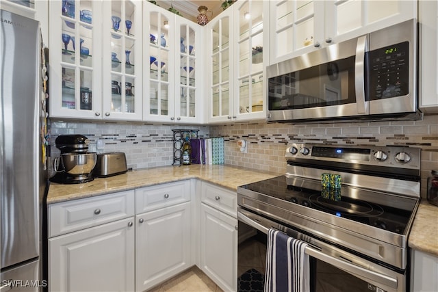 kitchen with white cabinets, decorative backsplash, stainless steel appliances, and light stone counters