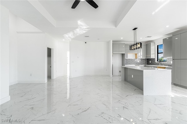 kitchen with backsplash, hanging light fixtures, gray cabinetry, and ceiling fan